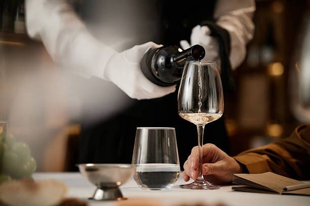 Sommelier häller vin i ett glas vid ett dukat middagsbord