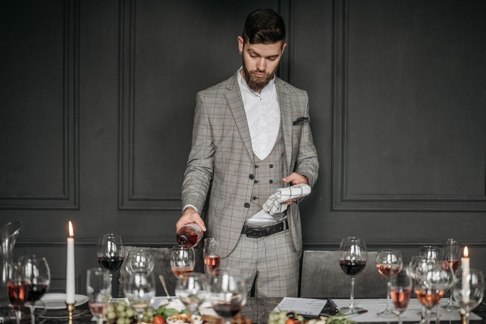 Sommelier häller vin vid ett dukat middagsbord med levande ljus