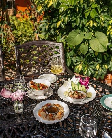 Elegant dukning med små maträtter och glas i en grönskande trädgård